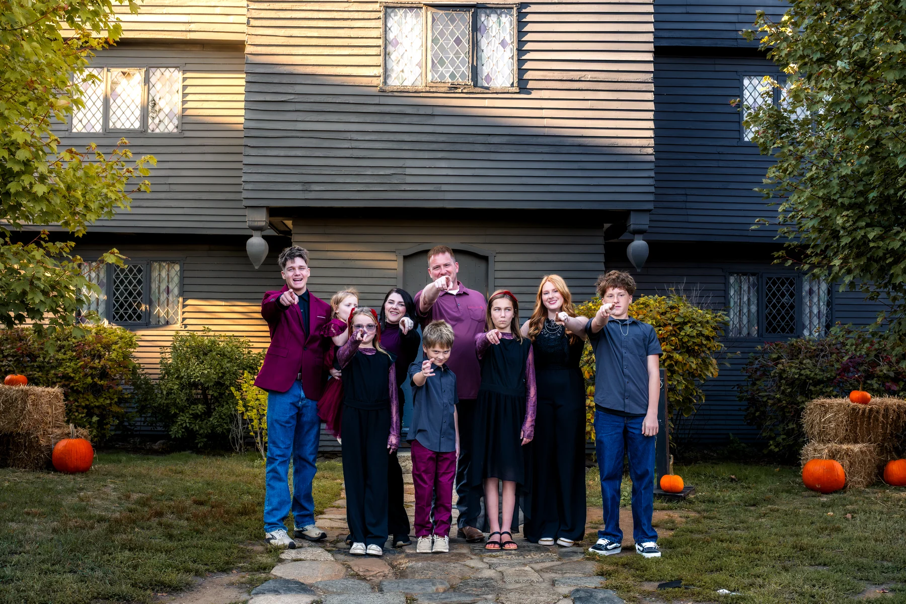 A family casting playful spells outside the Witch House